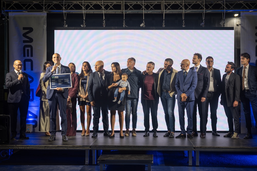 Famiglie e collaboratori sul palco, con un bambino in braccio