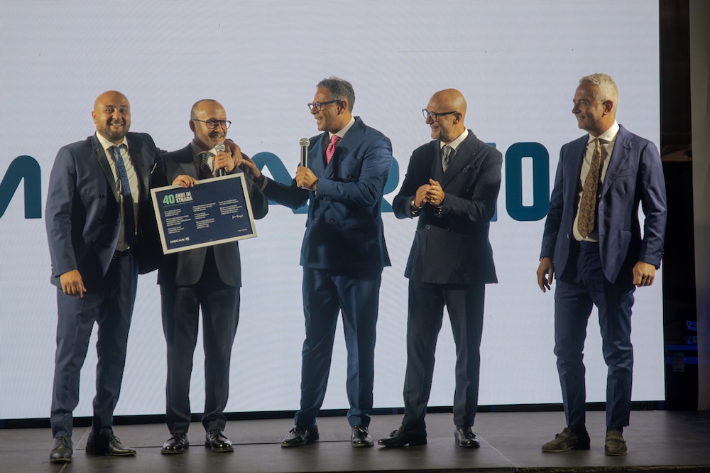 Cinque persone sul palco durante la consegna della targa
